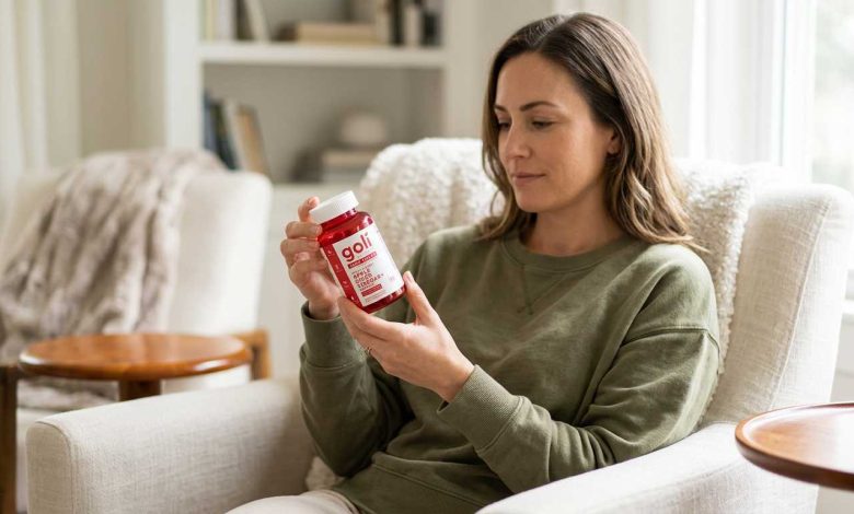 Woman at home reading a single red Goli zero sugar bottle during a calm daily routine