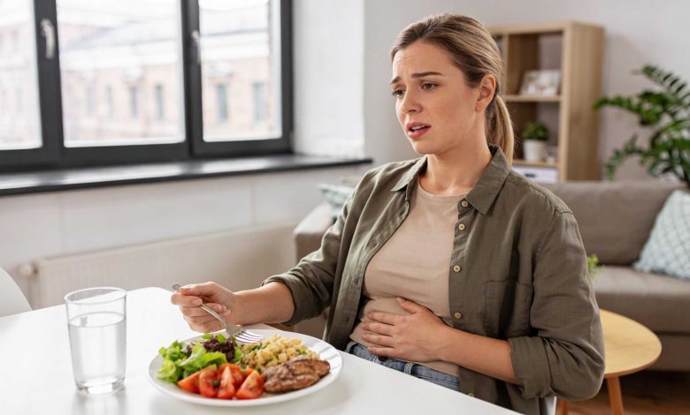 Woman holds her abdomen during a meal, illustrating copper iud bloating discomfort in daily life.